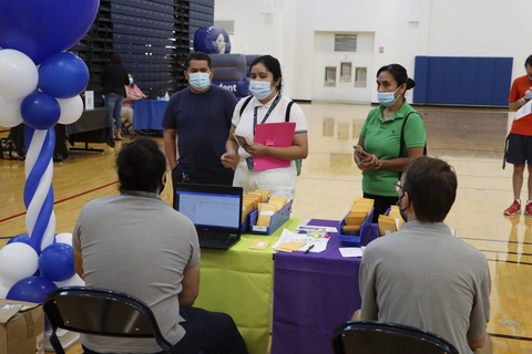 Students wait at a check-in table inside a gym during residence hall move-in and orientation activities.